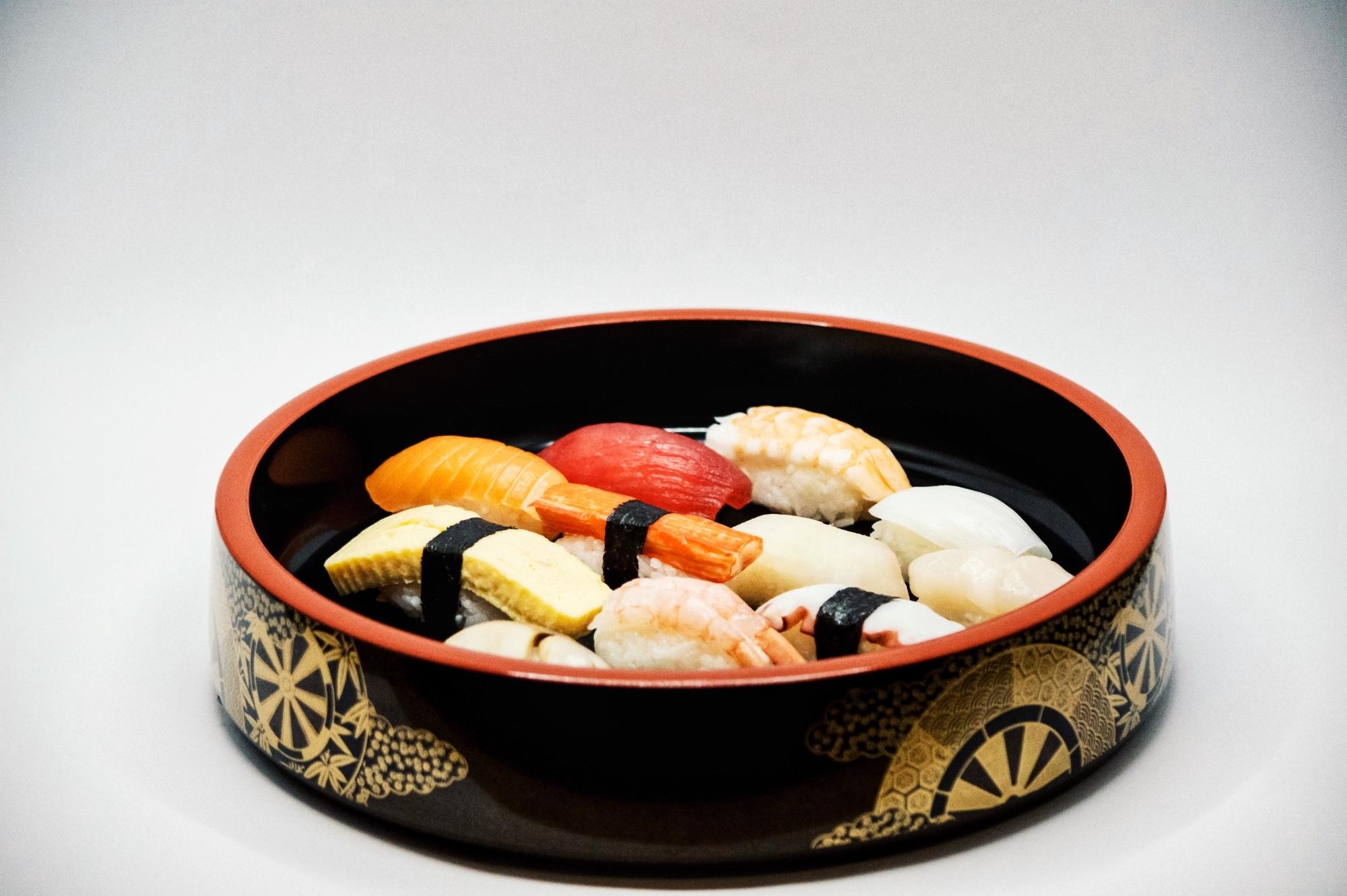 Traditionelle Sushi-Platte mit verschiedenen Nigiri, darunter Garnelen, Lachs und Thunfisch, serviert in einer dekorativen Schale im japanischen Stil